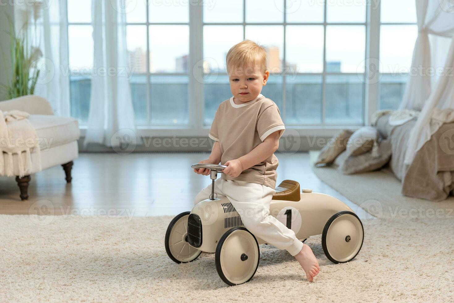 Happy child at home. Little toddler boy driving big vintage toy car and having fun. Smiling kid playing at home. Baby boy playing with toy in living room indoors. photo