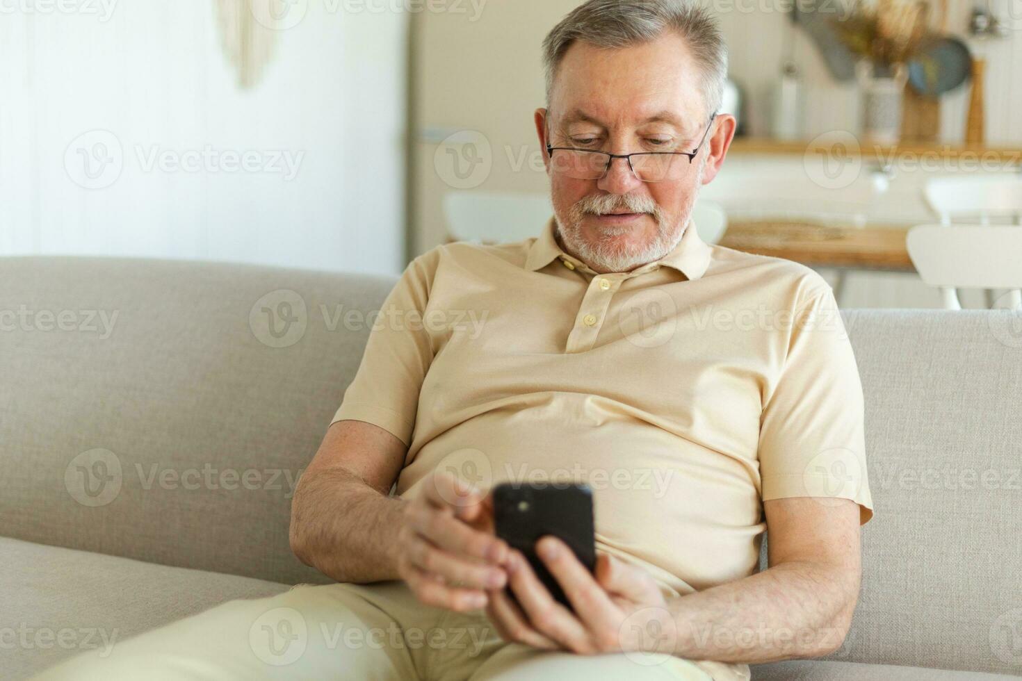 Happy middle aged senior man holding using smartphone touch screen typing scroll page. Stylish older mature beard grandfather with cell phone using internet social media apps at home. Shopping online. photo