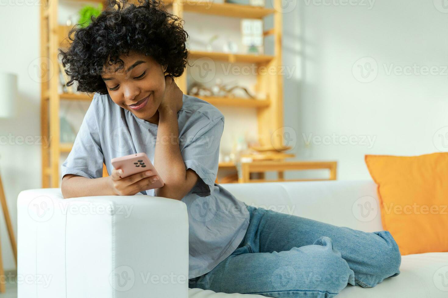 African girl holding smartphone touch screen typing scroll page at home. Woman with cell phone surfing internet using social media apps playing game. Shopping online Internet news cellphone addiction. photo