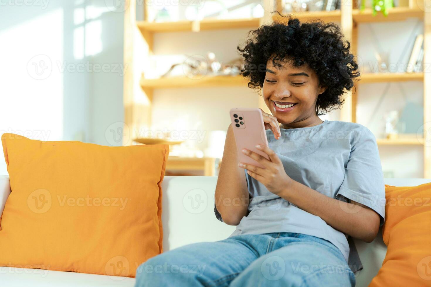 African girl holding smartphone touch screen typing scroll page at home. Woman with cell phone surfing internet using social media apps playing game. Shopping online Internet news cellphone addiction. photo
