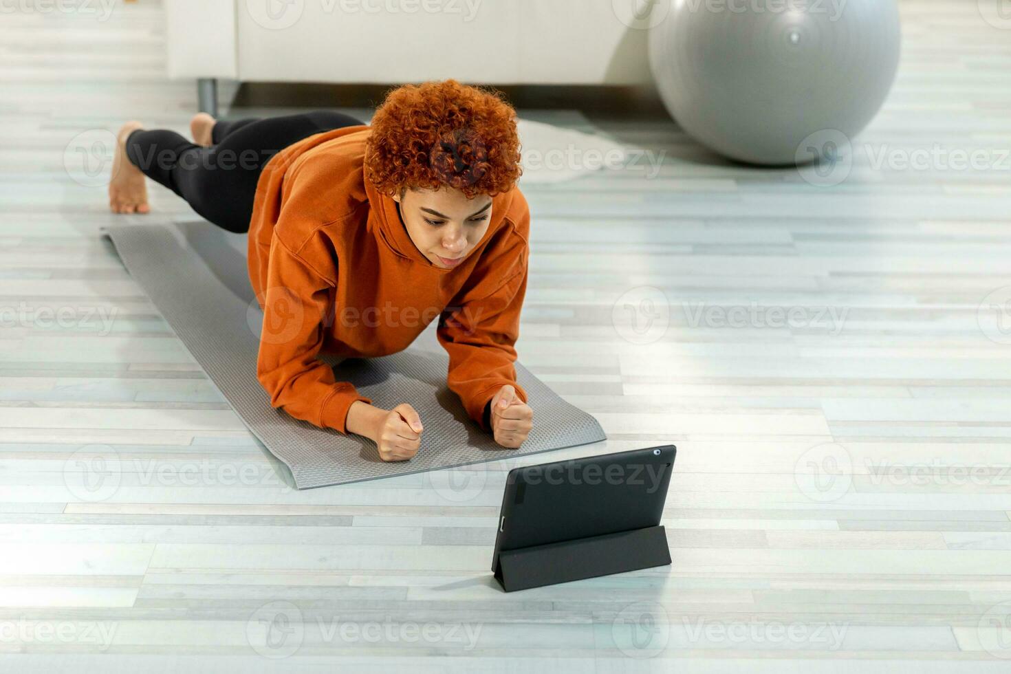 aptitud rutina de ejercicio capacitación. joven sano ajuste africano niña haciendo tablón ejercicio en yoga estera en piso a hogar. atlético mujer en ropa de deporte formación pilates deporte y aptitud física. foto