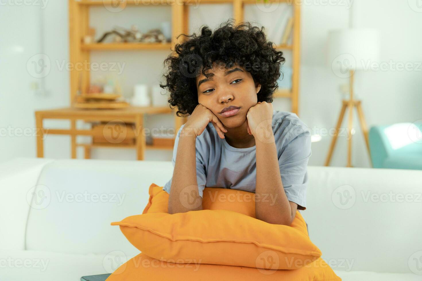 African american sad thoughtful pensive unmotivated girl sitting on sofa at home indoor. Young african woman ponder look tired after long day. Girl feels depressed offended lonely upset heartbreak. photo