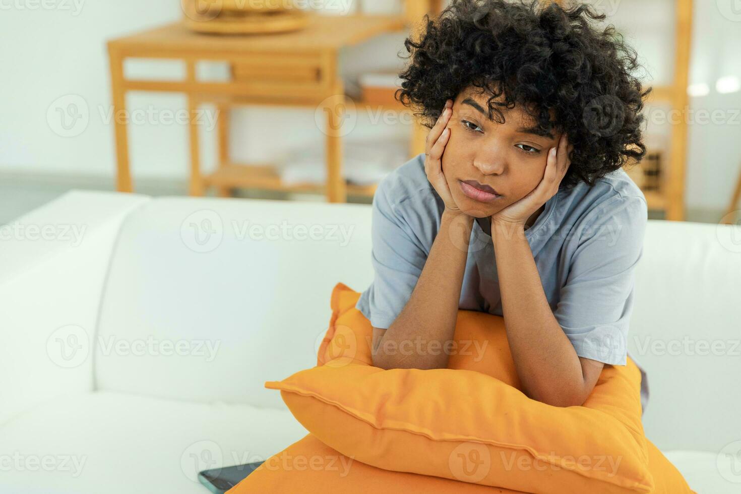 African american sad thoughtful pensive unmotivated girl sitting on sofa at home indoor. Young african woman ponder look tired after long day. Girl feels depressed offended lonely upset heartbreak. photo