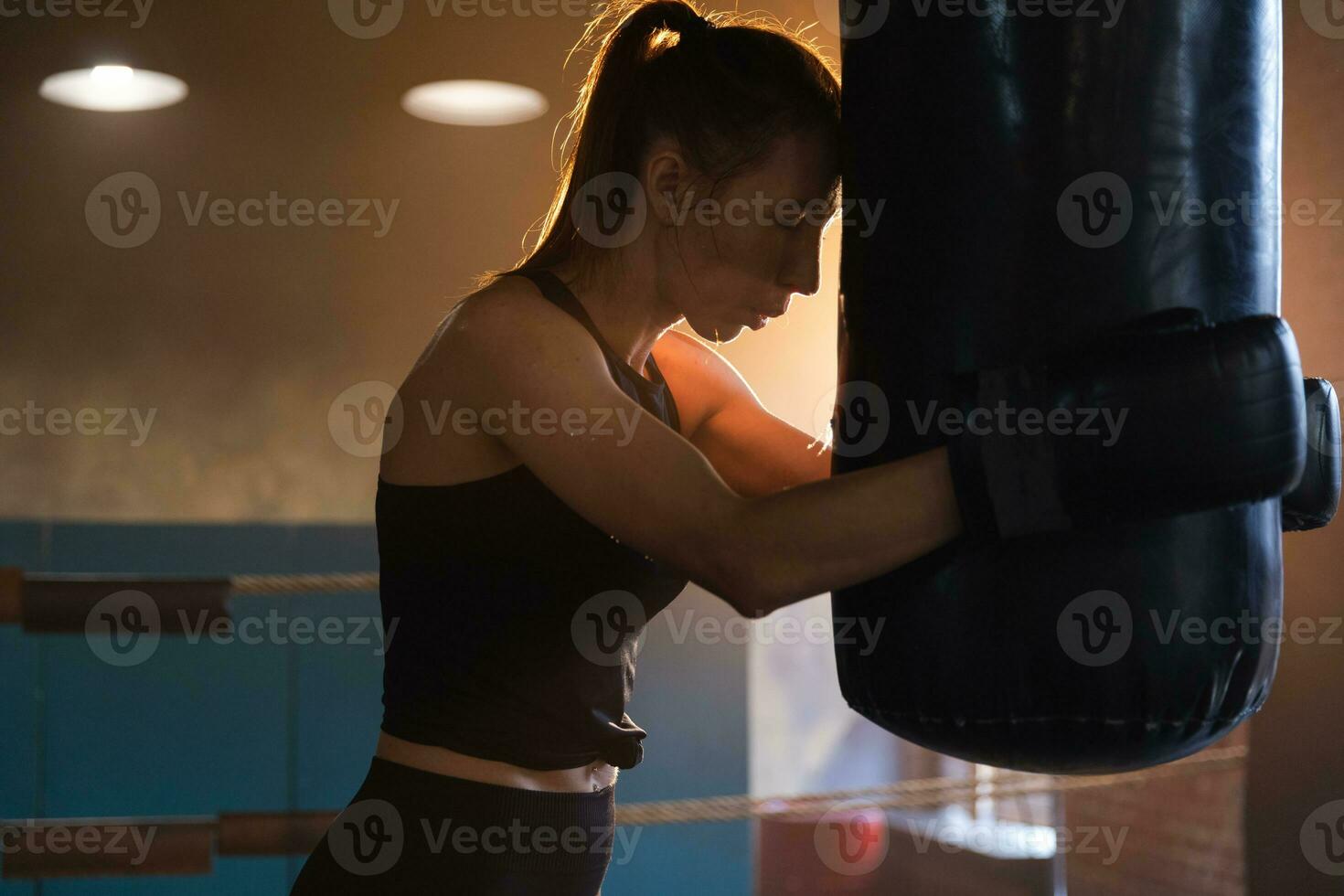 Women self defense girl power. Strong woman fighter resting after fight training on boxing ring. Strong girl tired after punching boxing bag. Training day in gym. Strength fit body workout training. photo