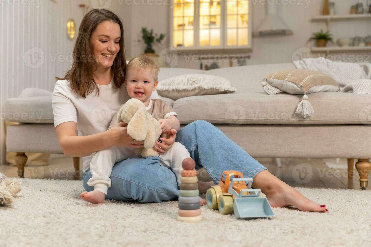 Happy family at home. Mother and baby boy playing with toys at home indoors. Little toddler child and babysitter nanny having fun together. Young woman mom kid son rest in living room. photo