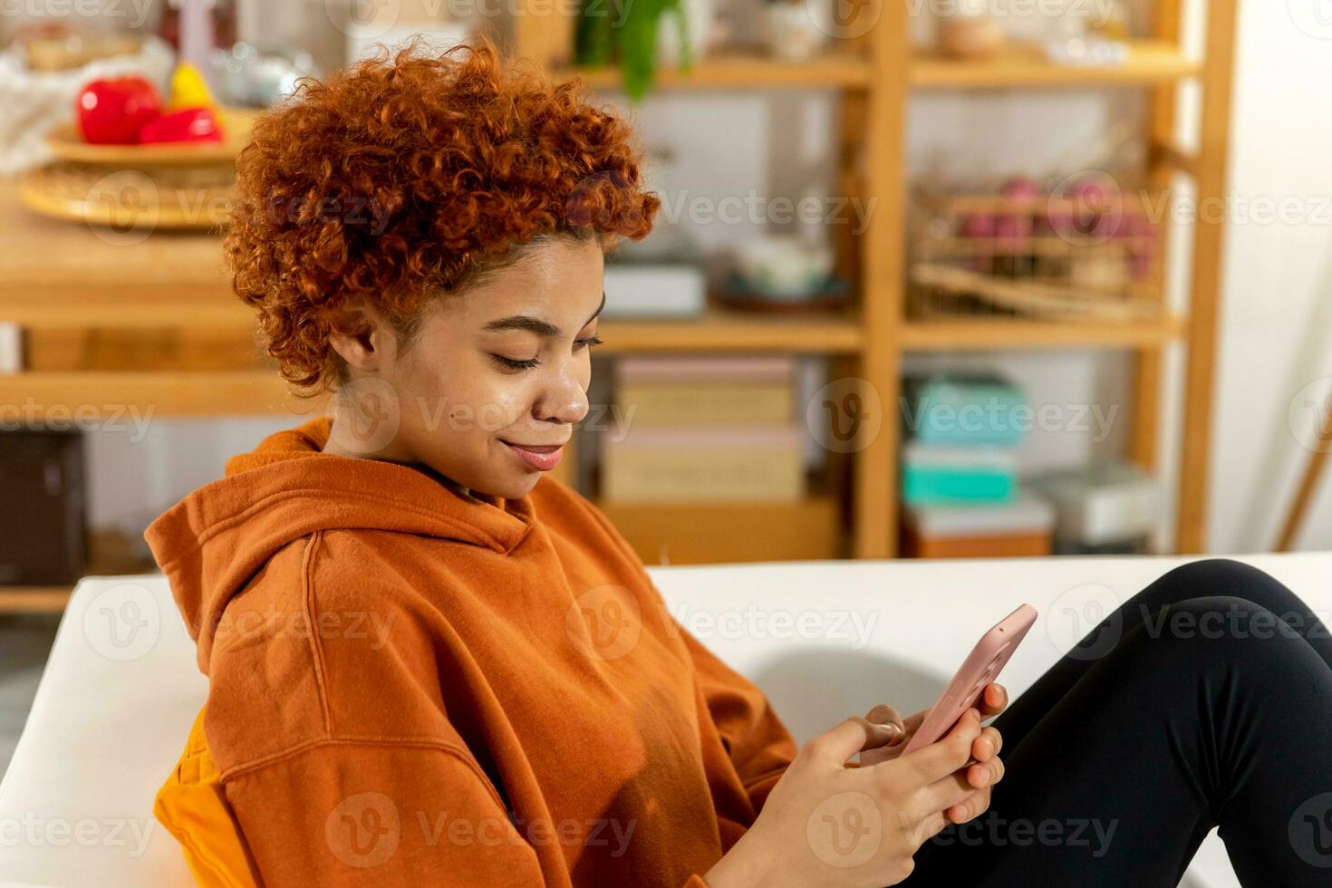 African girl holding smartphone touch screen typing scroll page at home. Woman with cell phone surfing internet using social media apps playing game. Shopping online Internet news cellphone addiction. photo