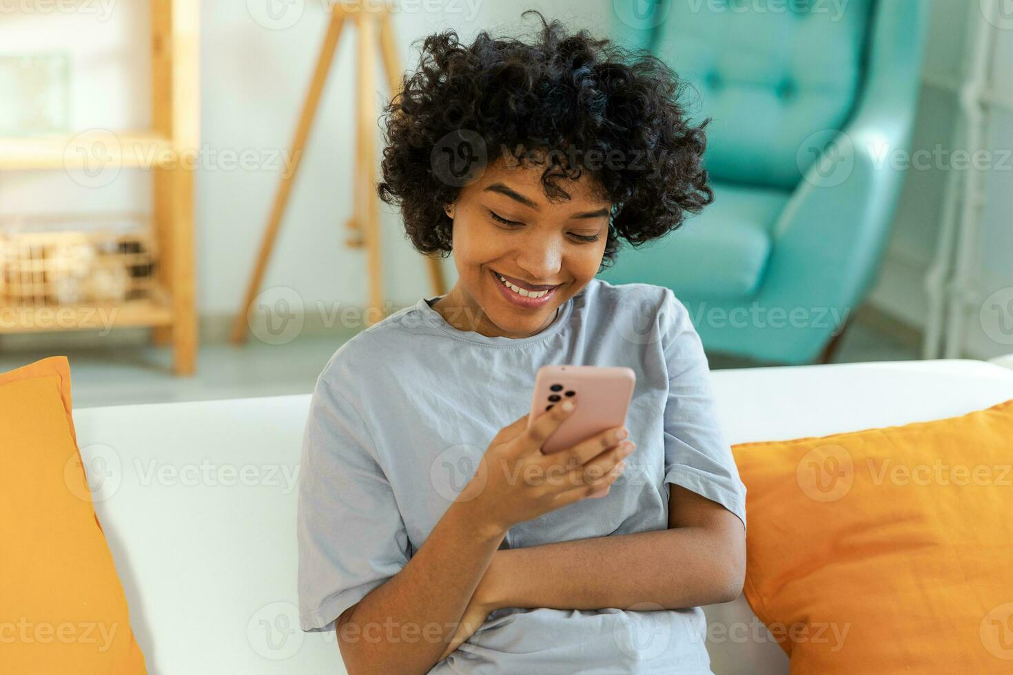 African girl holding smartphone touch screen typing scroll page at home. Woman with cell phone surfing internet using social media apps playing game. Shopping online Internet news cellphone addiction. photo