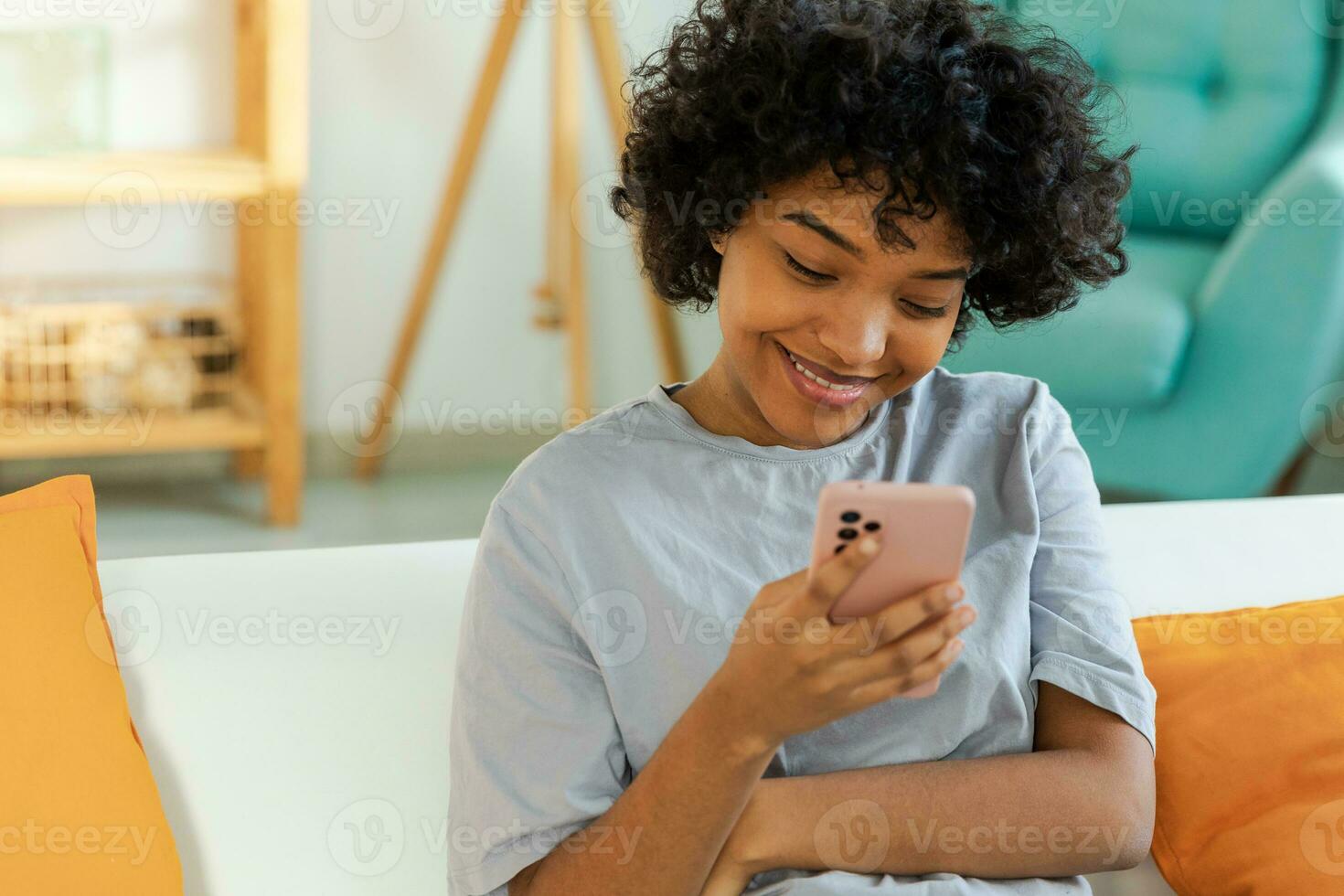 African girl holding smartphone touch screen typing scroll page at home. Woman with cell phone surfing internet using social media apps playing game. Shopping online Internet news cellphone addiction. photo