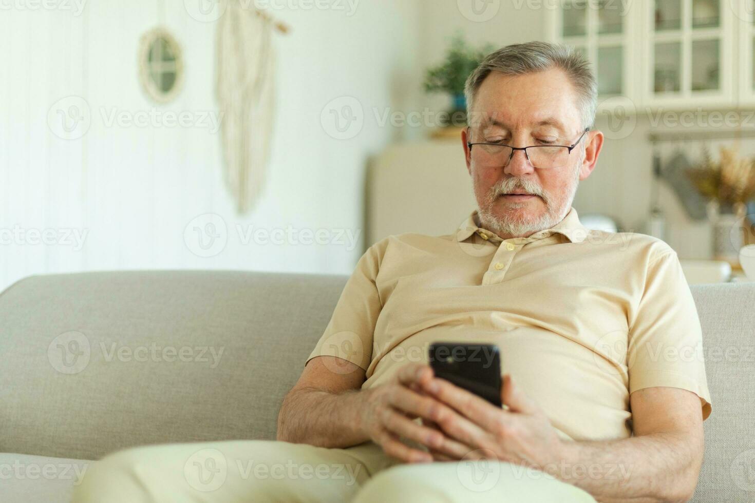 Happy middle aged senior man holding using smartphone touch screen typing scroll page. Stylish older mature beard grandfather with cell phone using internet social media apps at home. Shopping online. photo