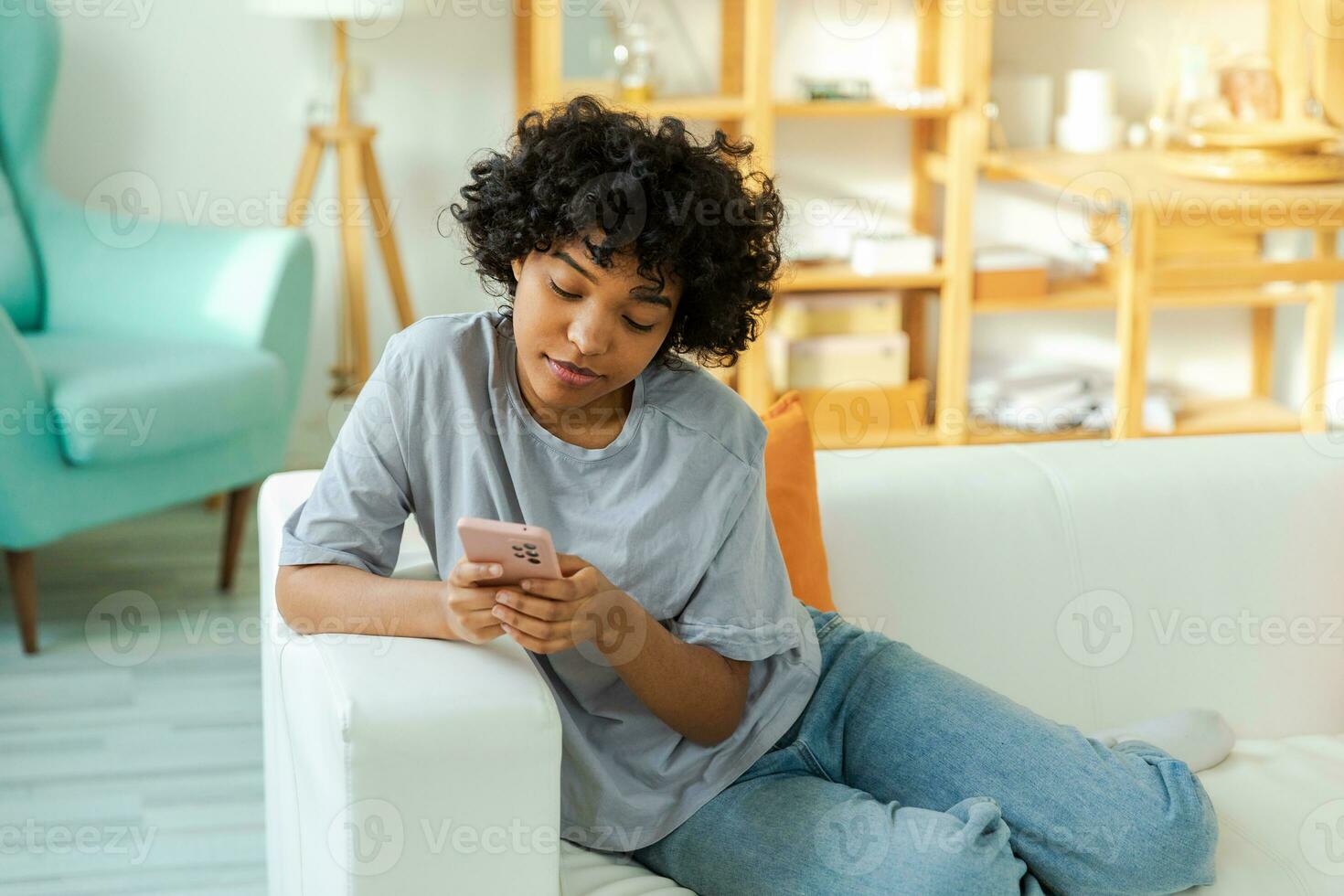 African girl holding smartphone touch screen typing scroll page at home. Woman with cell phone surfing internet using social media apps playing game. Shopping online Internet news cellphone addiction. photo