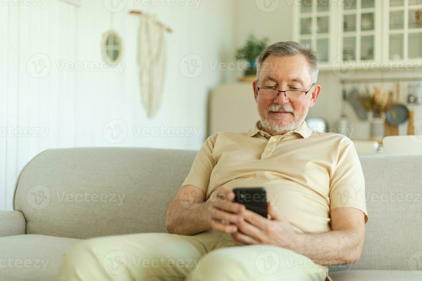 Happy middle aged senior man holding using smartphone touch screen typing scroll page. Stylish older mature beard grandfather with cell phone using internet social media apps at home. Shopping online. photo