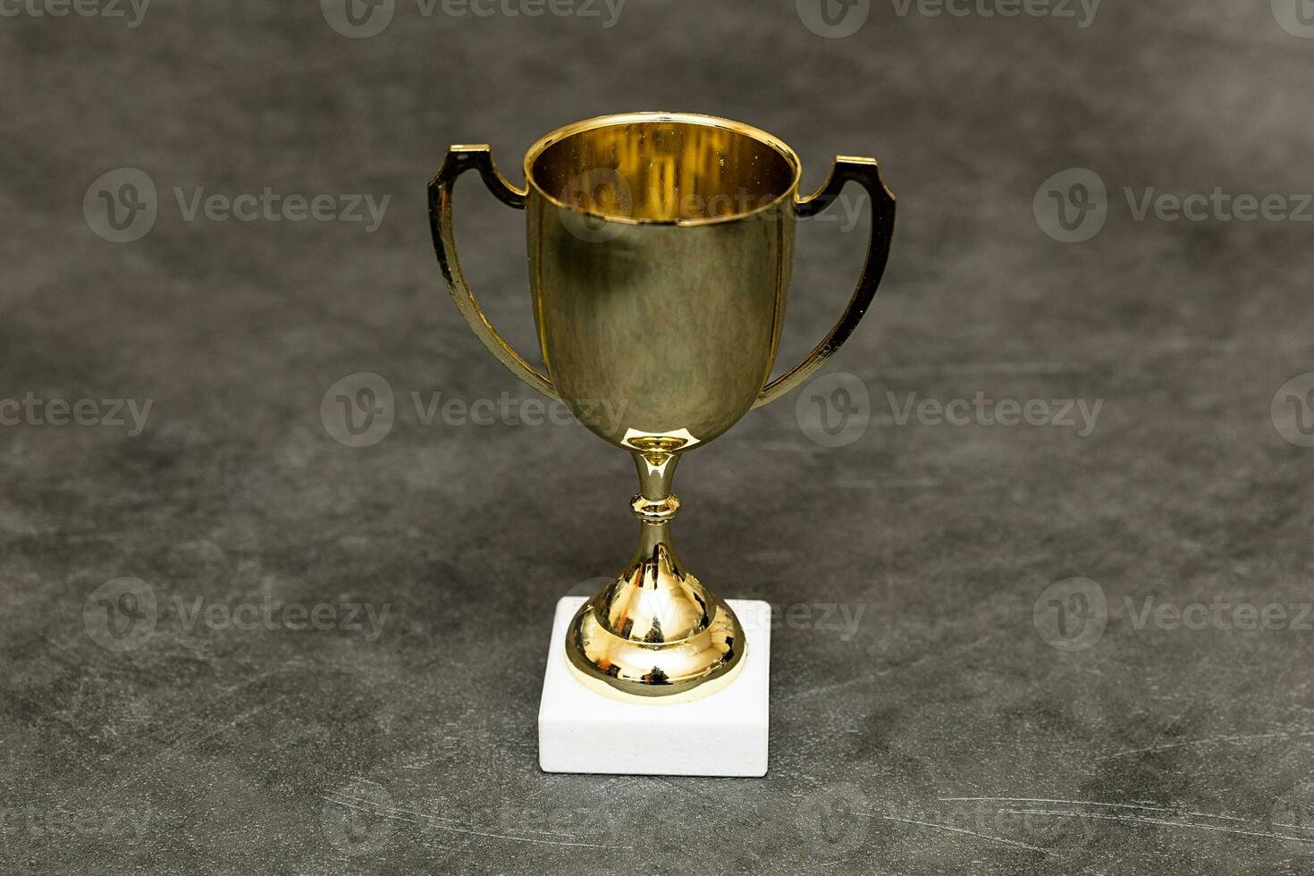 Simply design winner or champion gold trophy cup on concrete stone grey background. Victory first place of competition. Winning or success concept. Top view copy space. photo