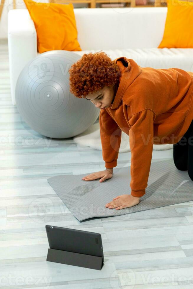 Fitness Workout training. Young healthy fit african girl doing sports exercise on yoga mat on floor at home. Athletic woman in sportswear have training workout for weight loss. Sport and fitness. photo