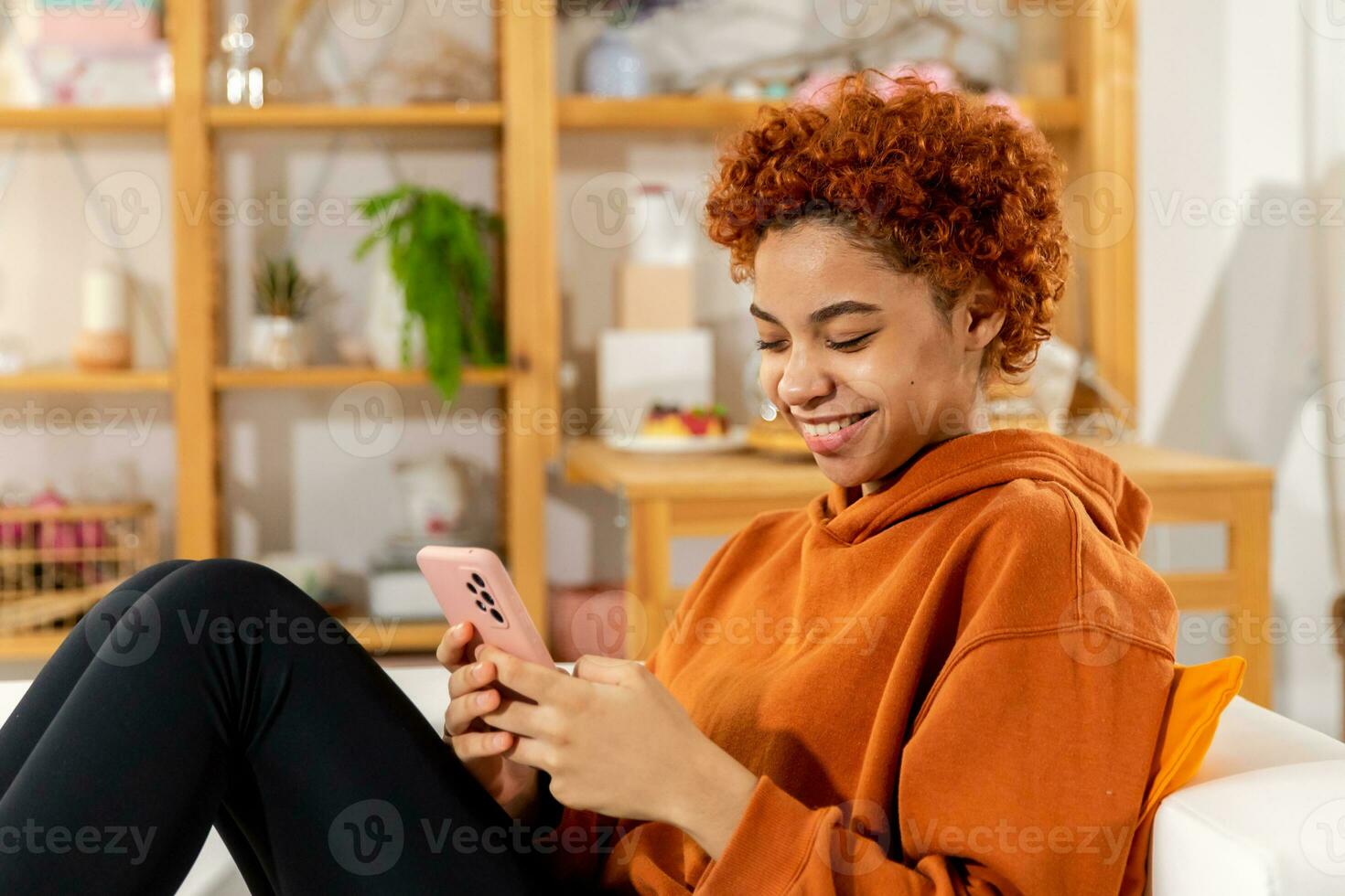 African girl holding smartphone touch screen typing scroll page at home. Woman with cell phone surfing internet using social media apps playing game. Shopping online Internet news cellphone addiction. photo
