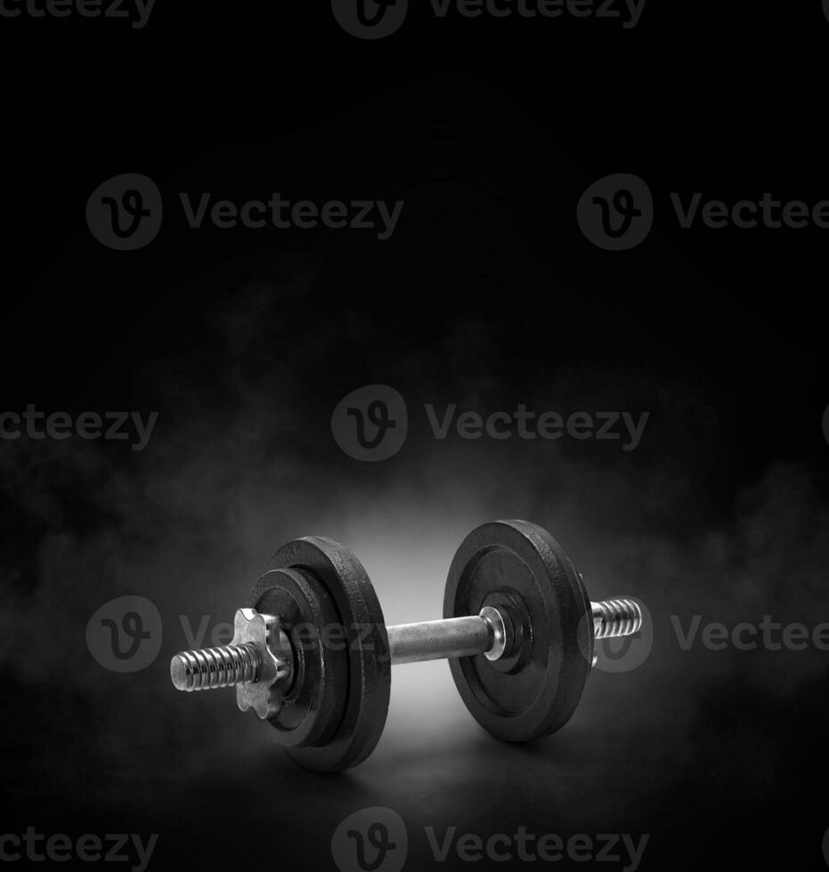 black dumbbell with on black background with smoke photo