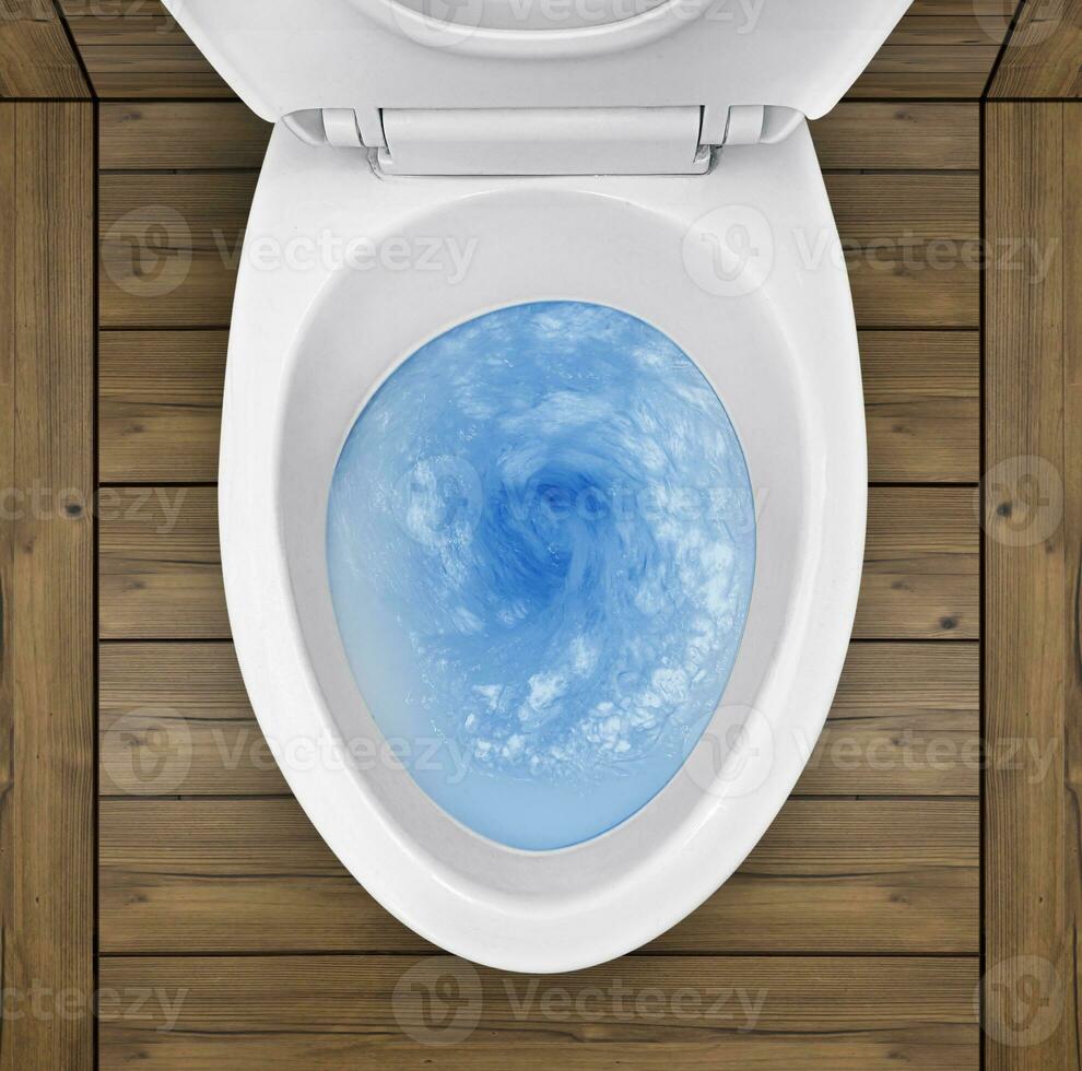 Top view of toilet bowl, blue detergent flushing in it photo