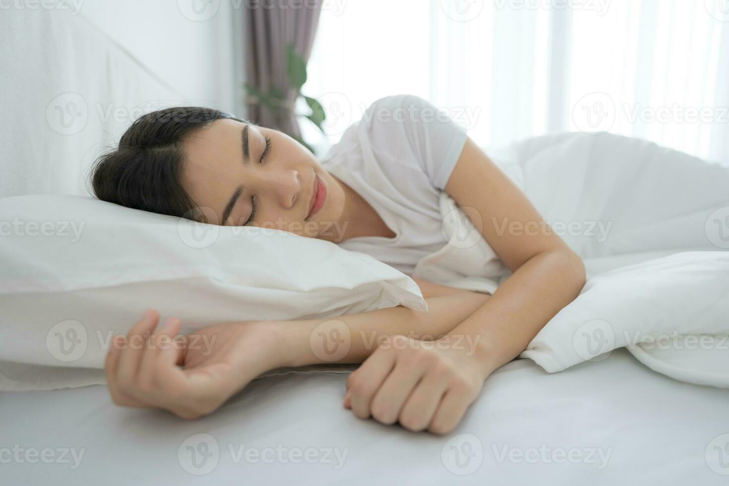 joven mujer dormido en un cómodo blanco dormitorio. foto