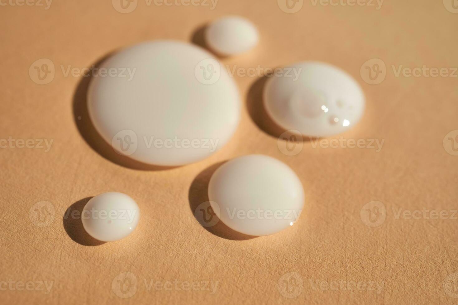 Drops of white milk on a beige background. photo