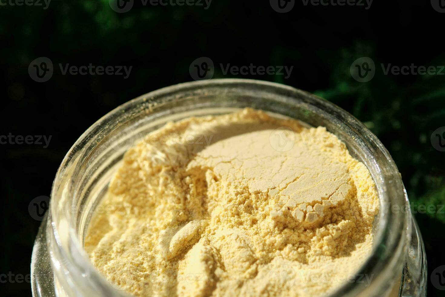 An open jar of a yellow turmeric facial scrub showing off its texture. photo