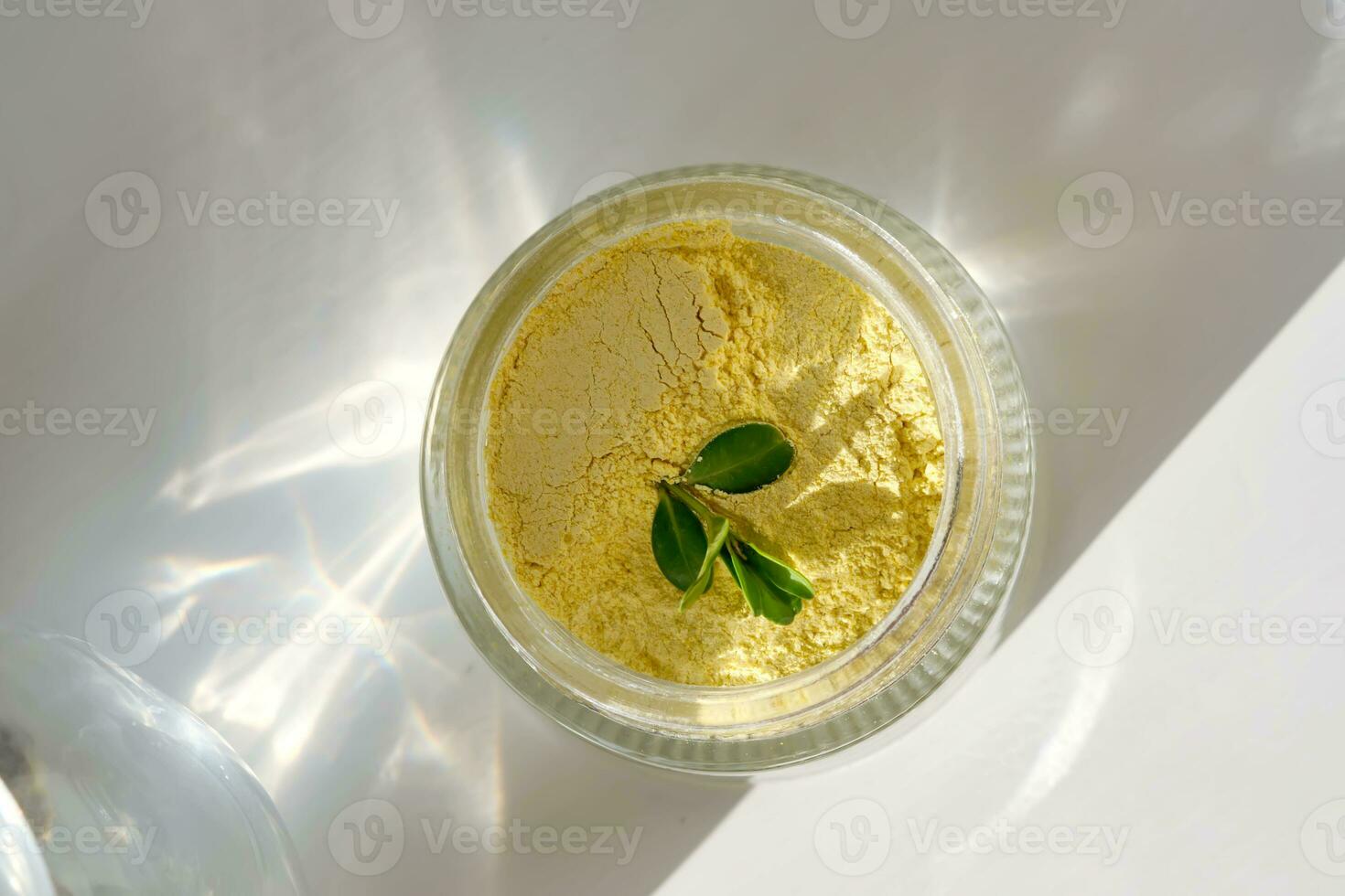 An open jar of a yellow turmeric facial scrub showing off its texture. photo