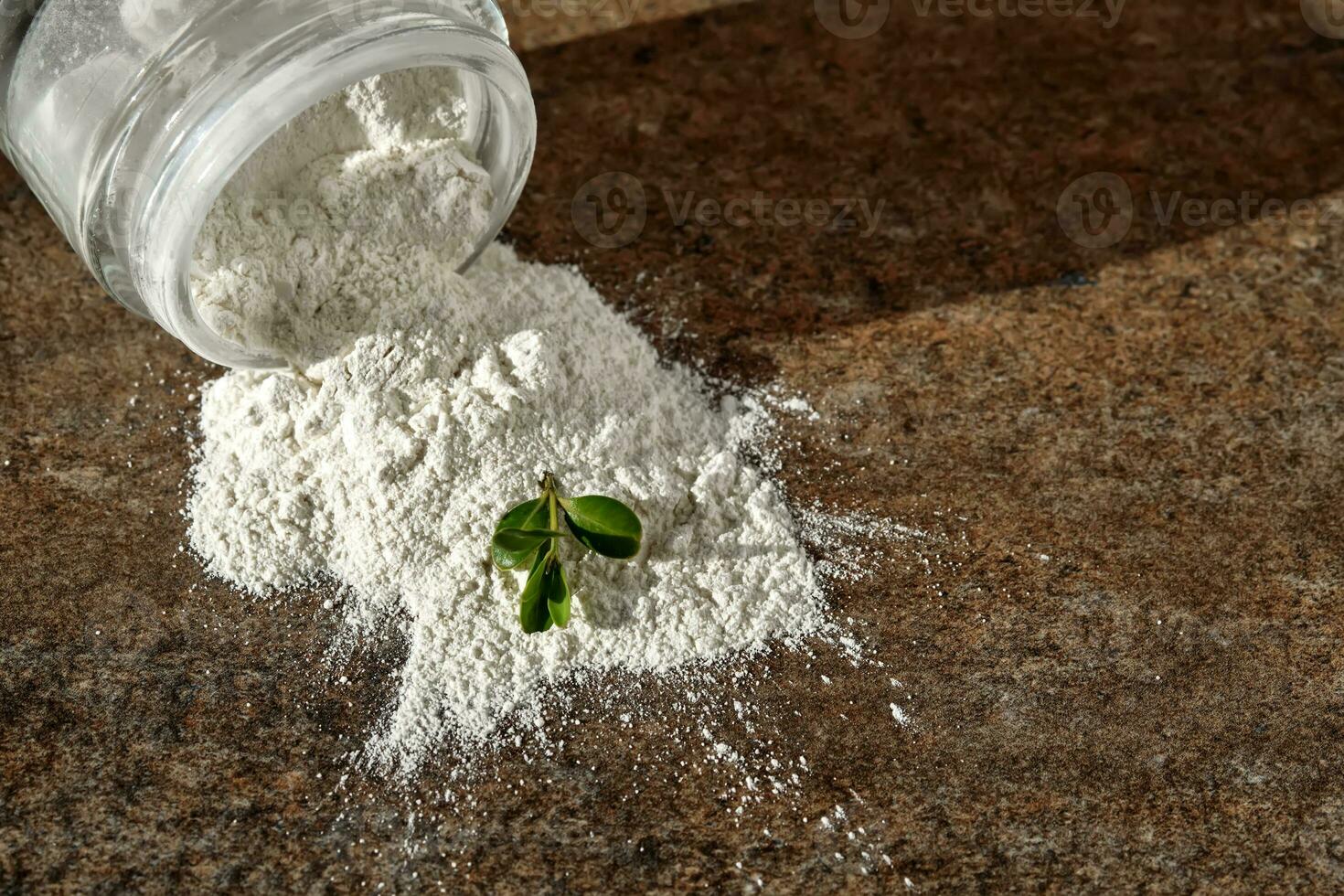 An open jar of facial scrub powder with a green sprig. photo