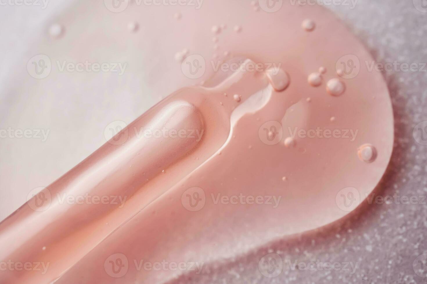 A pipette with a pink cosmetic lies in a drop. photo