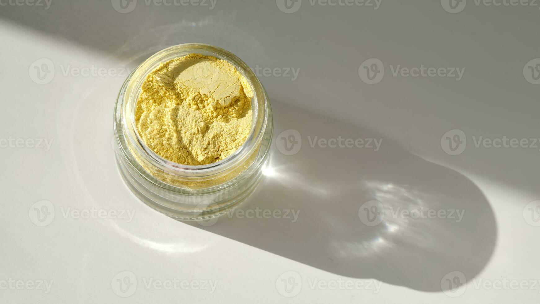 An open jar of a yellow turmeric facial scrub showing off its texture. photo