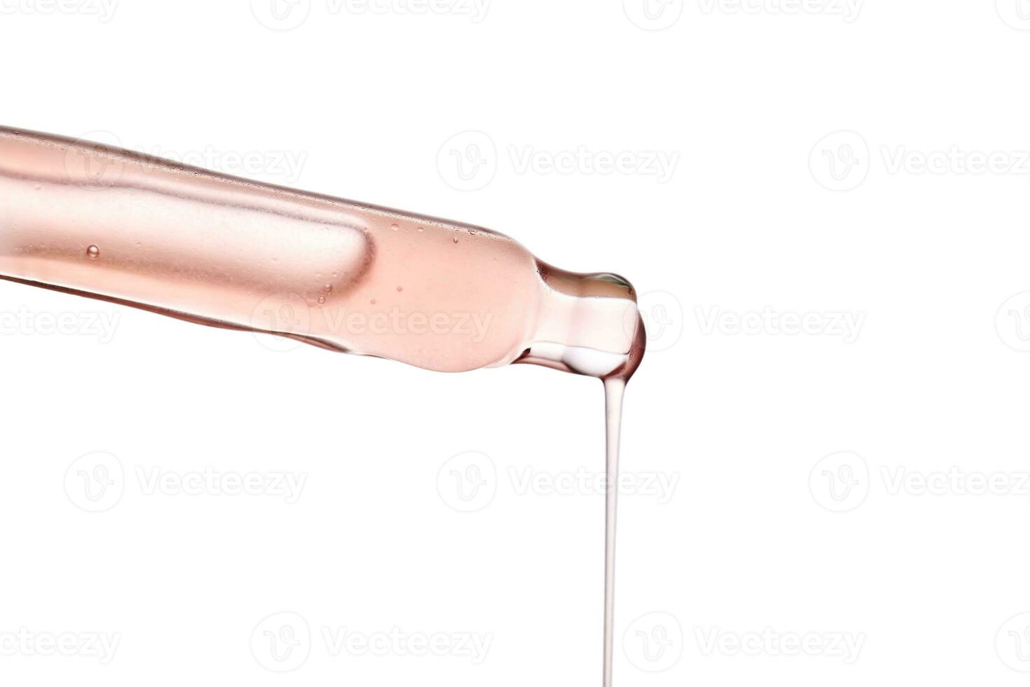 Pipette with a viscous pink cosmetic close-up. photo