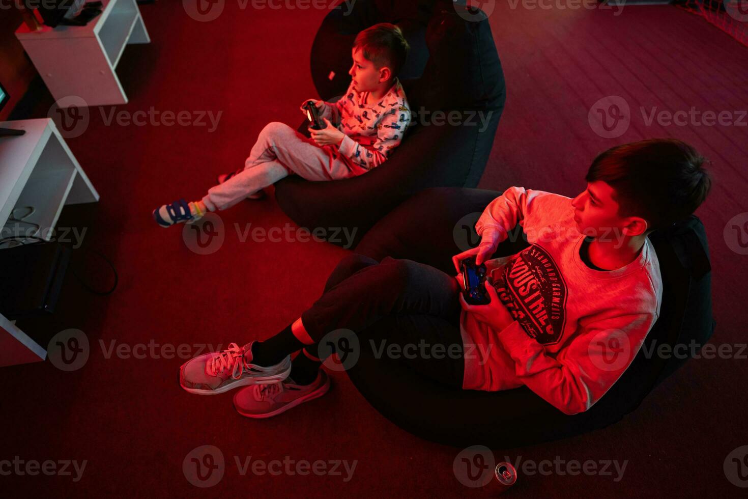 Two boys gamers play gamepad video game console in red gaming room. photo