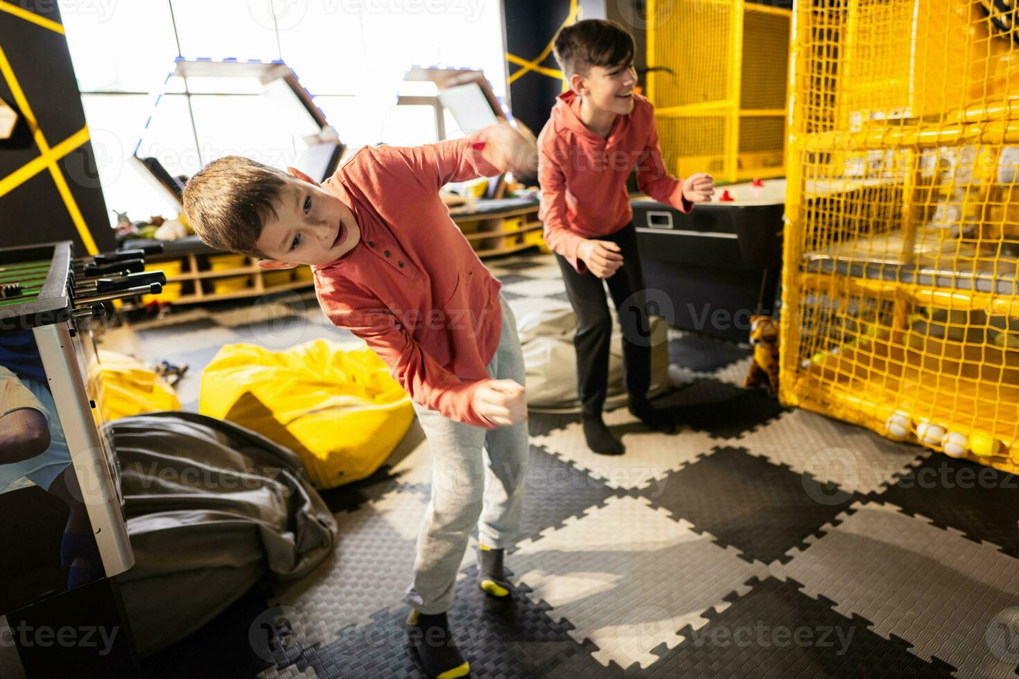 Two brothers riding with modern video game console by sensor at kids play center. photo