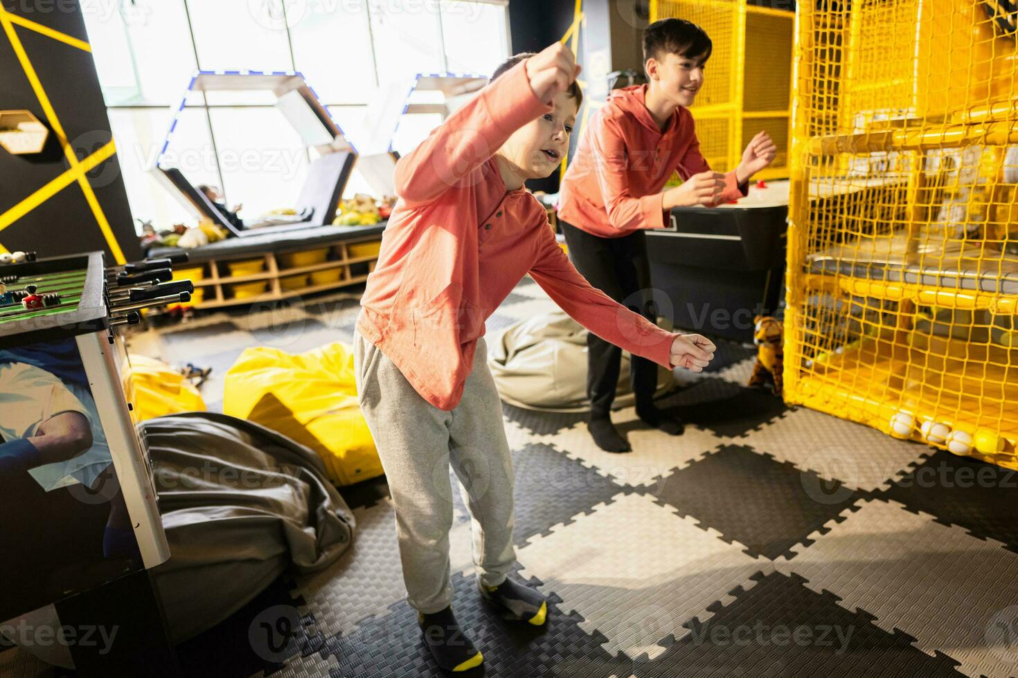Two brothers riding with modern video game console by sensor at kids play center. photo