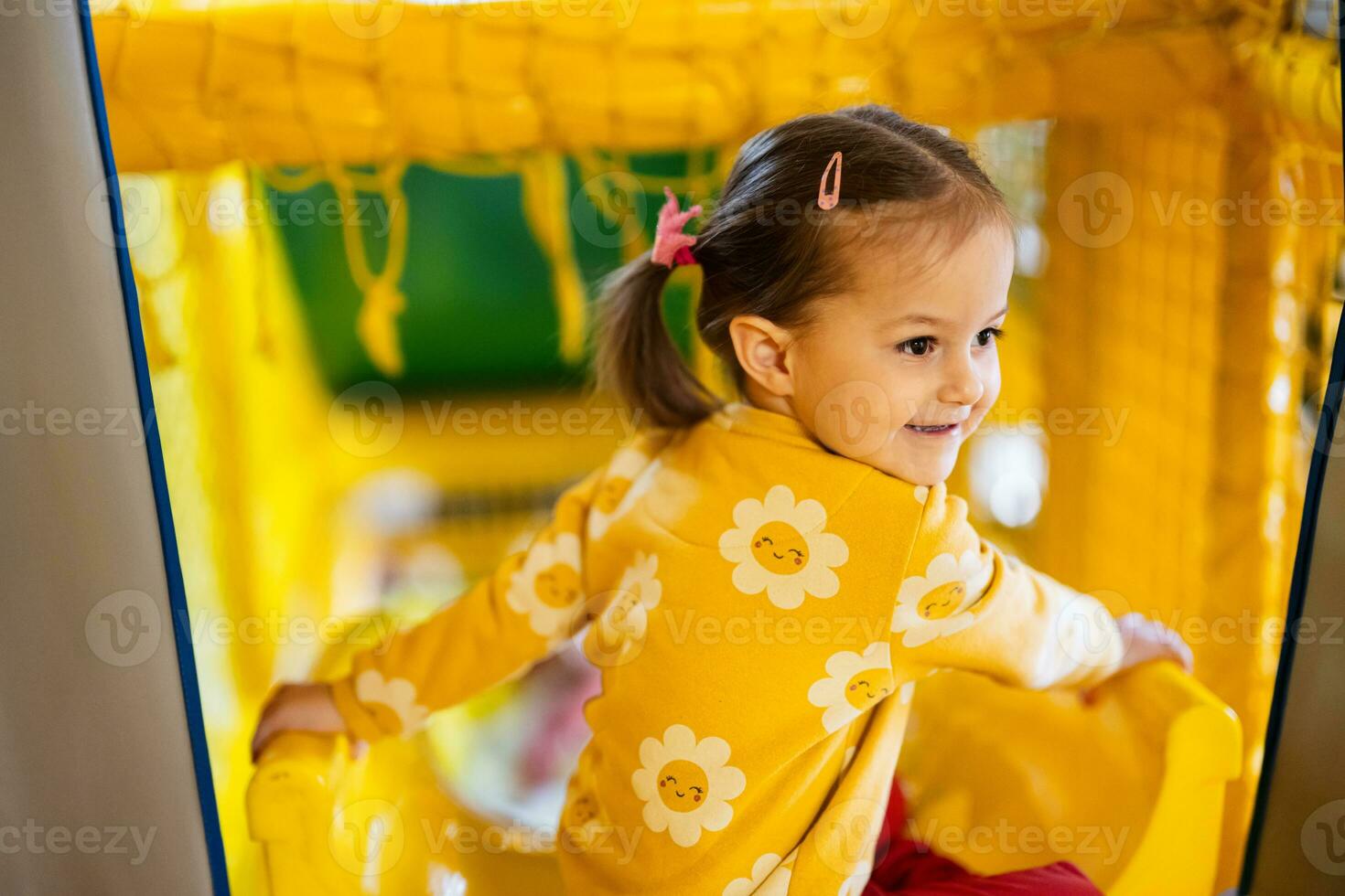 Baby girl kid slide at yellow playground park. Child in active entertaiments. photo
