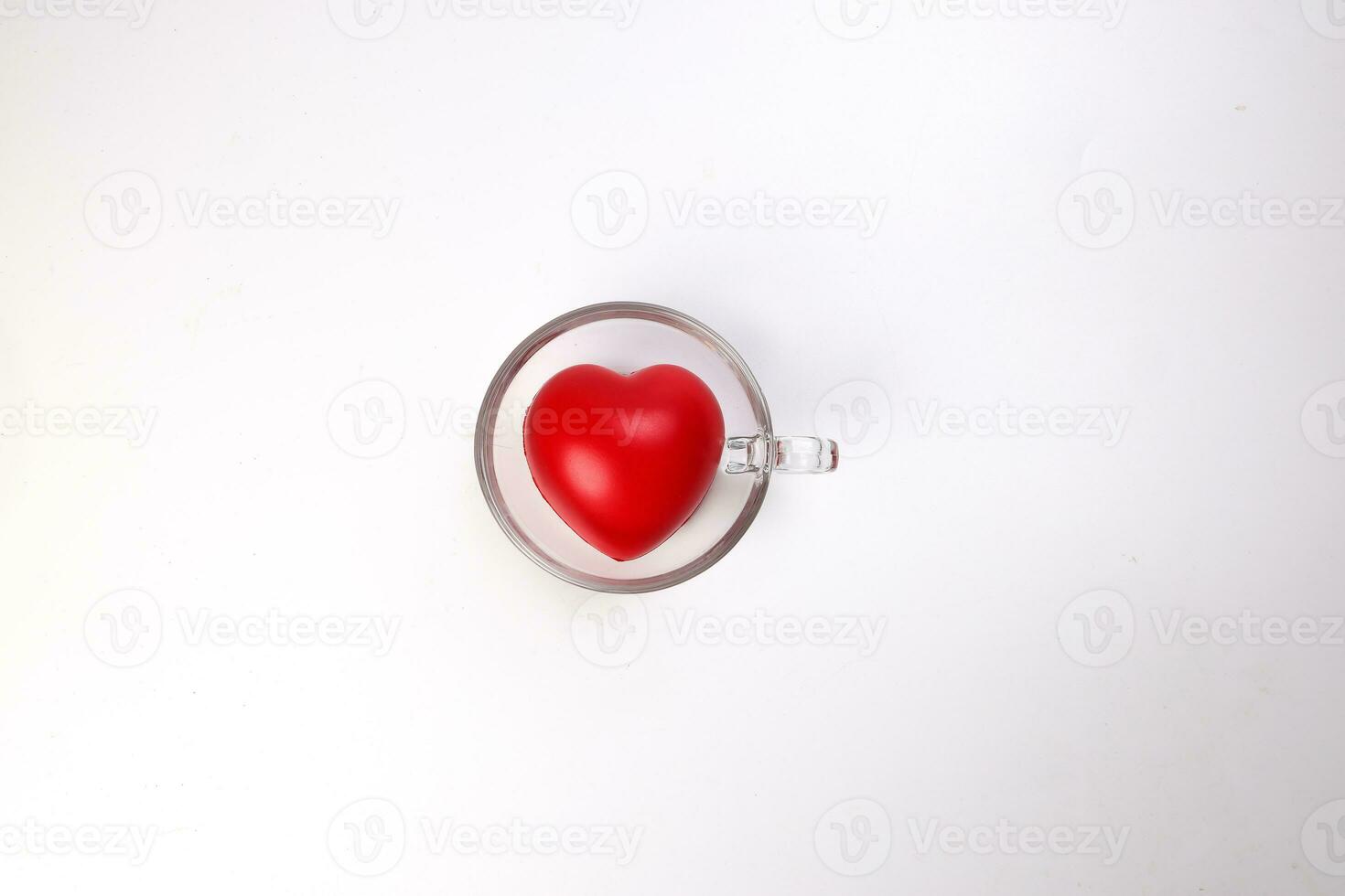 transparent glass coffee tea cup saucer with three dimension 3d red hart symbol inside on white background copy text space top view photo