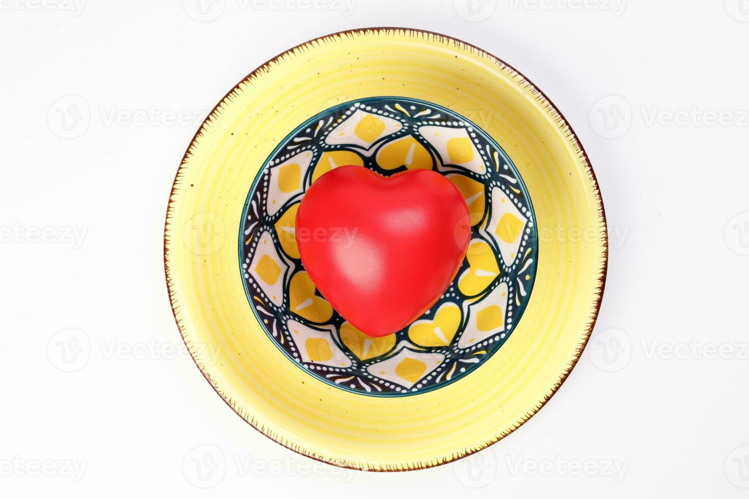 ceramic decorated food bowl yellow plate with three dimension 3d red hart symbol inside on white background copy text space top view photo