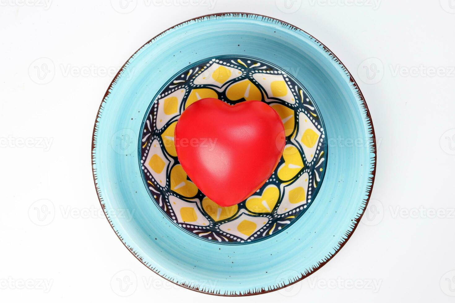 ceramic decorated food bowl blue plate with three dimension 3d red hart symbol inside on white background copy text space top view photo