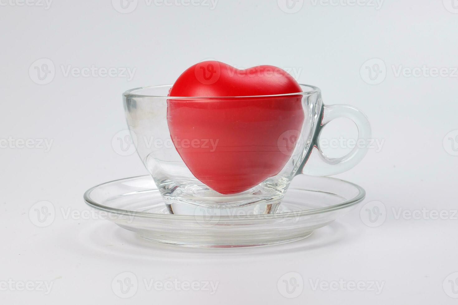 transparent glass coffee tea cup saucer with three dimension 3d red hart symbol inside on white background copy text space photo