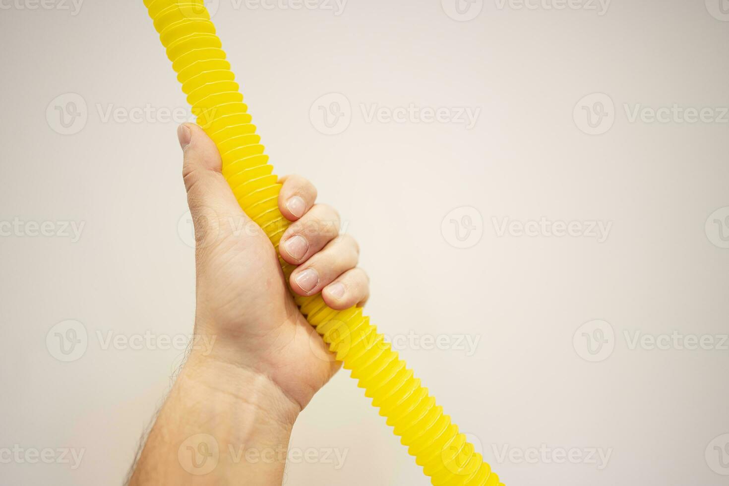 Close up of male hand holding yellow hose on background with copy space photo