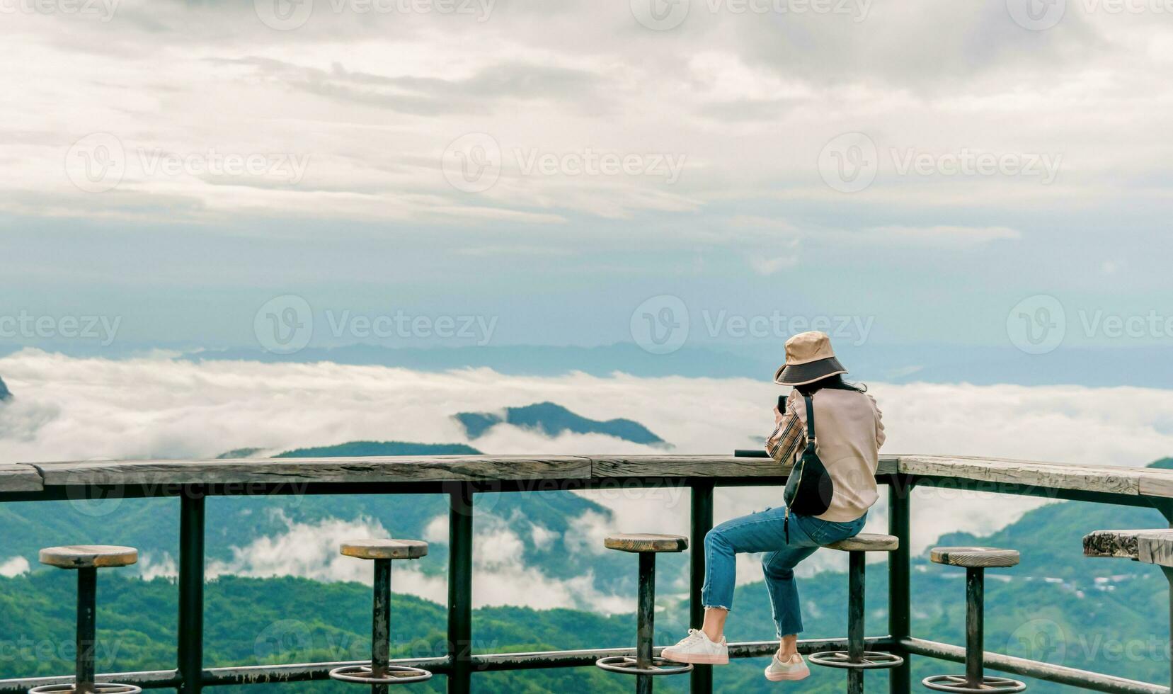 woman sitting on wooden balcony looking at mountain and fog view travel photo