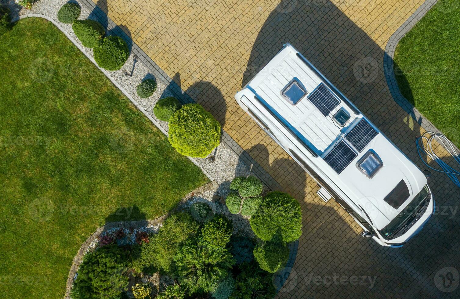 Modern Camper Van with Solar Panels Installed Staying on Residential Driveway Aerial View photo