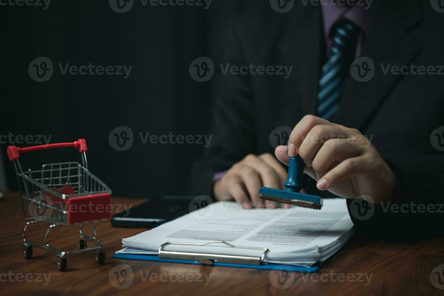 Man hand stamping approval signing on document or paperwork contract at desk. photo