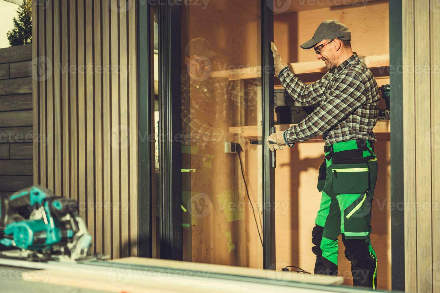 Contractor Installing Aluminium Frame Window Glass Doors Inside a Shed photo