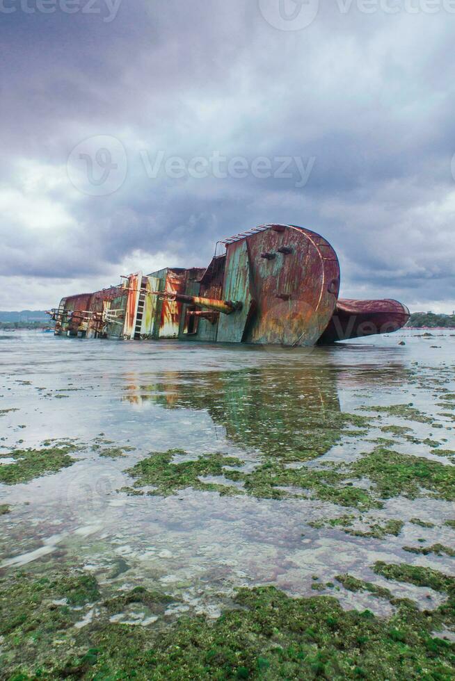 Shipwreck on the white sand beach of Pangandaran, West Java, Indonesia. the ship was sunk due to illegal fishing photo