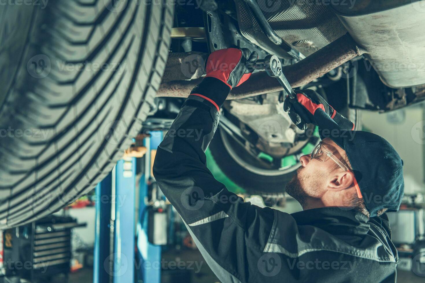 Mechanic Fixing Chassis Of Car In Garage. photo