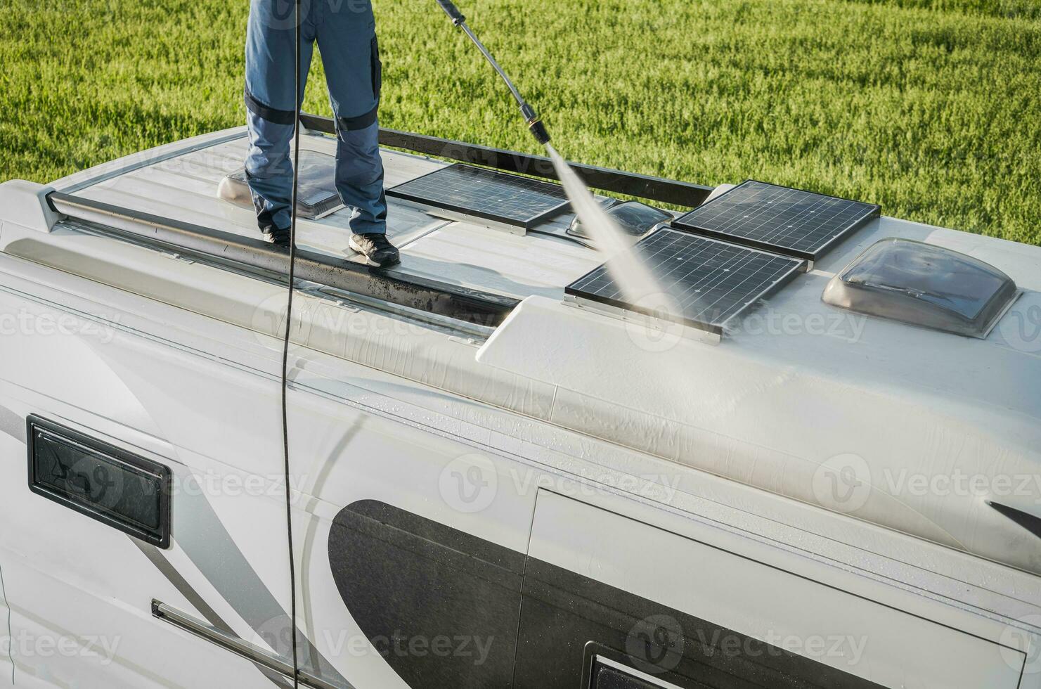 RV Industry Worker Cleaning Camper Van Roof and Motorhome Solar Panels photo