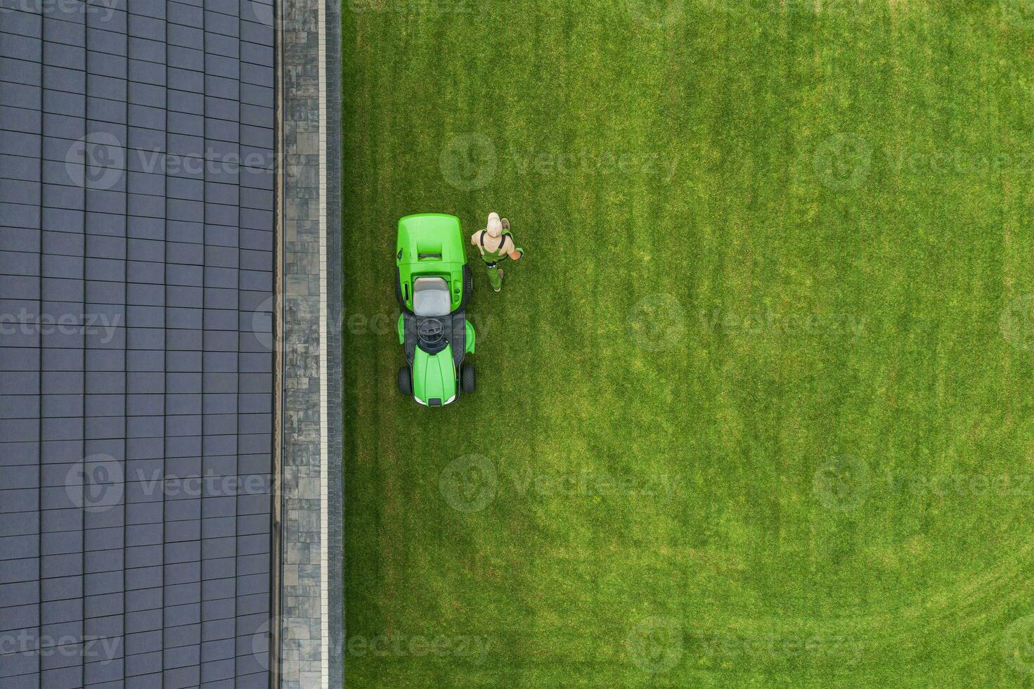 Aerial View of Riding Lawn Mower and Caucasian Gardener. photo