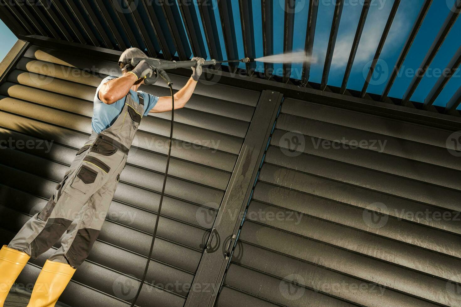 Worker Pressure Washing Modern Aluminium Made Car Port photo