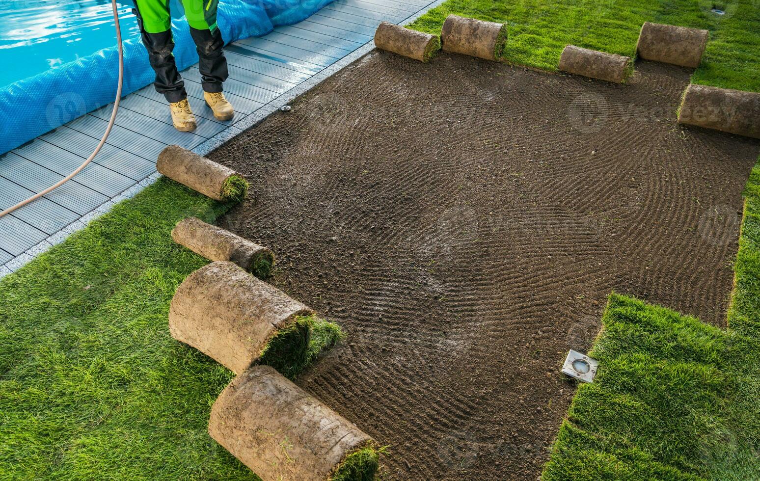 Landscaping Worker Rolling Out Turf Rolls in a Garden photo