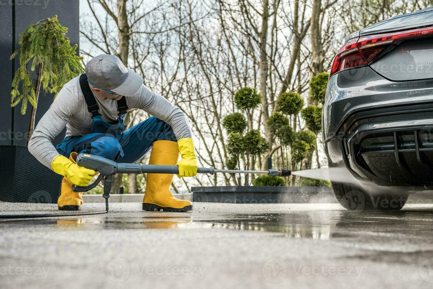 hombres presión Lavado su coche en frente de un casa foto