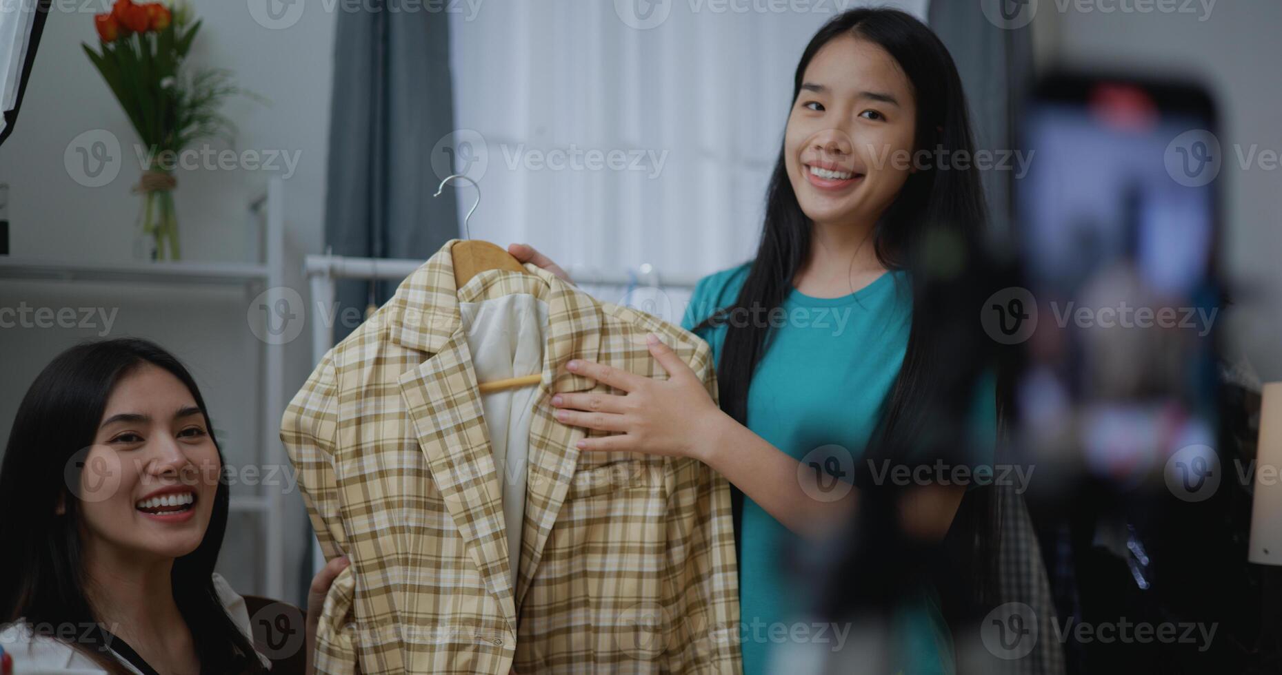 Young Asian female fashion designer using mobile phone live steaming photo