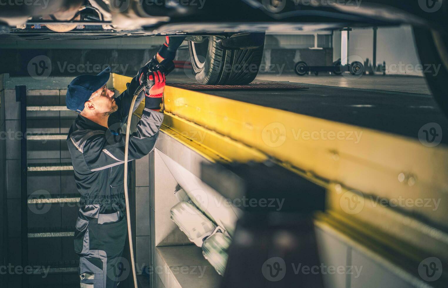 Car Mechanic Performing Vehicle Undercarriage Diagnostic Check photo